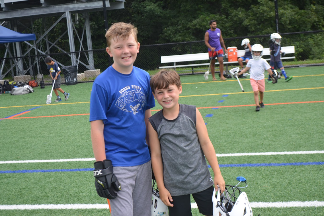 Two boys standing next to each other for a picture after playing lacrosse